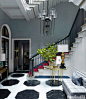 Vivid red carpet on the stairs and a black-and-white marble floor with boldly scaled octagons establish the entry's dynamic mood. Gambrel designed the large Viennese-inspired Suffolk chandelier, part of his lighting collection for Urban Electric. The cust