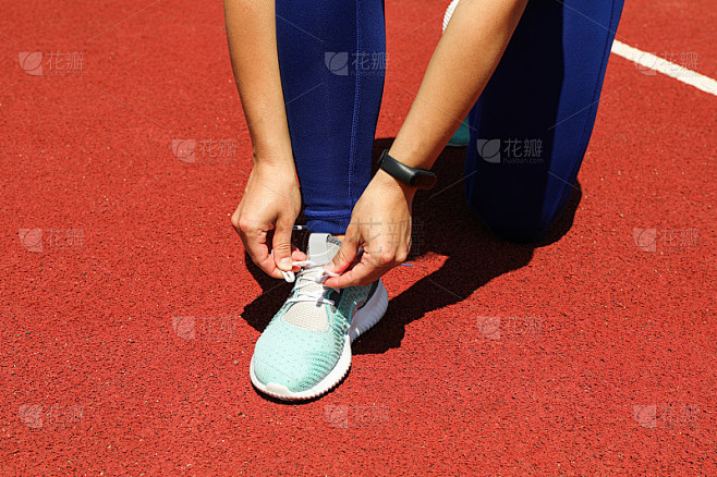 女孩系鞋带在红色的田径跑道，文字空间