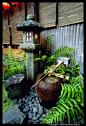 This hits almost all of our we-love-Japanese-gardens buttons. It's got the cool stone lantern, the rustic stone water well, a beautiful old rock, river rocks, and simple ferns to add softness and green.