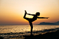 Young healthy woman practicing yoga on the beach at sunset