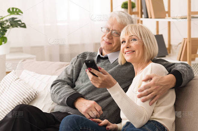 幸福的老年夫妇拥抱和看电视