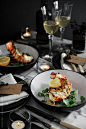 Lobster thermidor in bowls on a table with wine. by Darren Muir for Stocksy United