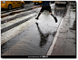 雨中，一名女子越过纽约联合广场路边的一个水洼，纽约。摄影师：Mark Abramson