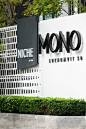 This may contain: a sign that says mono on it in front of a building with trees and bushes
