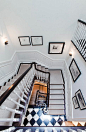 dark floors on steps with a light runner, black and white floor, white walls, black railing, white spindles: 