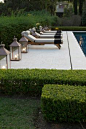 smooth palest limestone terrace with elegant loungers and lanterns | clipped hedges