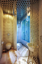 Shell-like wall tiles adorn the bathroom, where the lighting and faucet 'drip' from the ceiling.