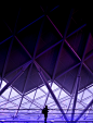 A silhouette of a person against the backdrop of a purple-hued steel structure