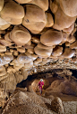 This may contain: a person standing in the middle of a cave filled with large rocks and rock formations