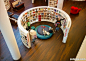 Love that large cushion... and the idea of being hugged by books! Creative children's library design.