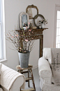 Sap bucket on a farm stool filled with spring budding twigs. Vintage frames in layers, fake mantel