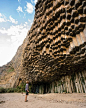 This may contain: a man standing in front of a giant rock formation with hexagonal blocks on it