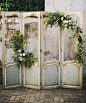 A vintage screen ceremony backdrop decorated with airplants and blooms | poppyandmintfloral.com | Photo by arielrenaephoto.com: 