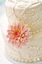 Ivory wedding cake with Victorian piping and a gorgeous floral accent.  Wedding