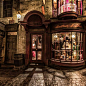 This may contain: an old fashion store in the middle of a cobblestone street at night time