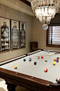 Fantastic games room features a tiered glass bottles chandelier, Arteriors Stedman 5 Light Iron Glass Chandelier, hanging over a pool table.