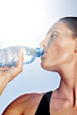 Close-up of a woman drinking water against sunny sky