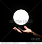 Bright light ball over human hand isolated on black background