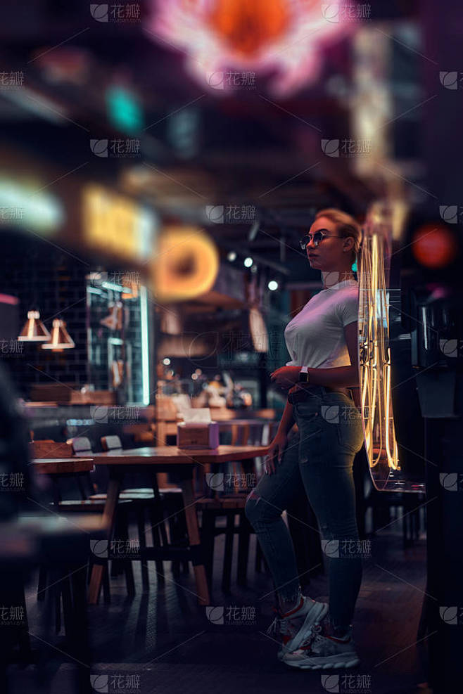 在霓虹灯酒吧戴着太阳镜的迷人女人正在为摄...