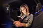 Woman with smartphone in her car at night.