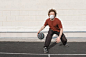 Man in Red Crew Neck T-shirt and Black Pants Sitting on Basketball Court