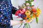 女人手里捧着一束白花、牡丹、风信子等花。教育。花商与顾客沟通在车间在工作室用鲜花。