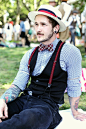 Mixing Patterns and Solids with straw boater hat with red and navy striped band, red dominant plaid bow tie, sky blue gingham button up shirt, black vest, deep red suspenders with contrasting white type and navy corduroy pants