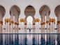 White arches and golden pillars make patterns by a reflection pool in a mosque