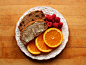 2 slices of whole wheat banana bread (1 with chocolate chips and 1 spread with Earth Balance), a sliced navel orange, and raspberries.