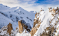 A hiker on a jagged mountain peak covered in snow