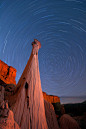 Hoodoos lit by campfire light at night during a long exposure to capture star trails.