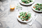 Plates of fresh salads and a glass of orange juice at a kitchen table