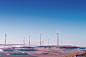 white wind turbine on grey desert under blue and white sky