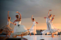 在日落期间跳舞在灰色天空下的白色礼服的5名妇女