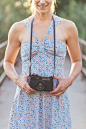 Smiling woman in dress using old camera.