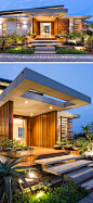 Uplighting, plants and a small pond welcome you to this home, while granite stairs that appear to be floating lead to the large front entrance of this modern home, that is adorned in timber cladding.