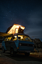 man sitting on top of blue van staring at sky during nighttime