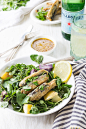 A dish with spinach, fish and lemons on a set table