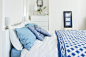 White walls, furniture and linen with splashes of bright blue textiles create a serene seaside bedroom.