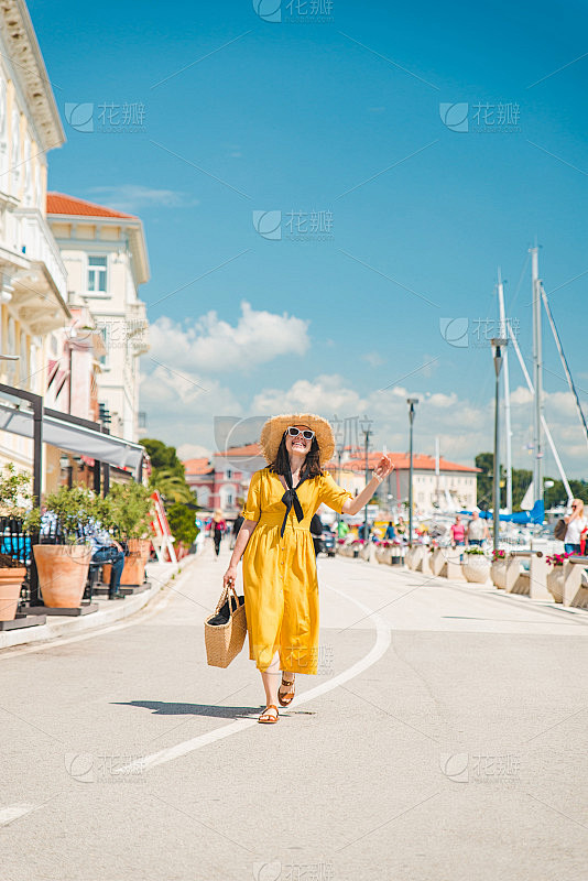 女人在黄色背心裙走在度假夏季城市度假概念