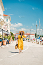 女人在黄色背心裙走在度假夏季城市度假概念
