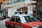 Red and white taxi car in a busy urban street in Tsim Sha Tsui