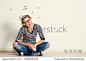 Portrait of happy female listening musical composition in earphones with sheet music and clef drawn on the wall. Young pretty Caucasian woman sitting on wooden floor in her house. -人物,编辑-海洛创意（HelloRF） - 站酷旗下品牌 - Shutterstock中国独家合作伙伴