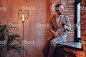 一個穿著法蘭絨西裝的時髦男人的肖像, 戴著眼鏡聽音樂, 電話和耳機坐在一個房間裡, 閣樓內部的窗臺上。 免版稅 stock photo