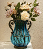 
铁艺玻璃台面花瓶，晶莹的蓝色，与前面纯洁的白色花瓶互相对应,