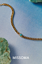 This may contain: a gold chain with a turquoise bead on it and the word missoma written below