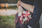 Bride holds a wedding bouquet of roses while wrapping arms around her groom