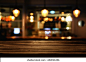 在抽象模糊餐厅灯光背景前木桌的图像。 库存照片