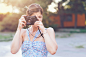 Smiling woman in dress using old camera.