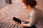 A woman with a blue painted nails holding and reading on an ipad tablet beside a walkway